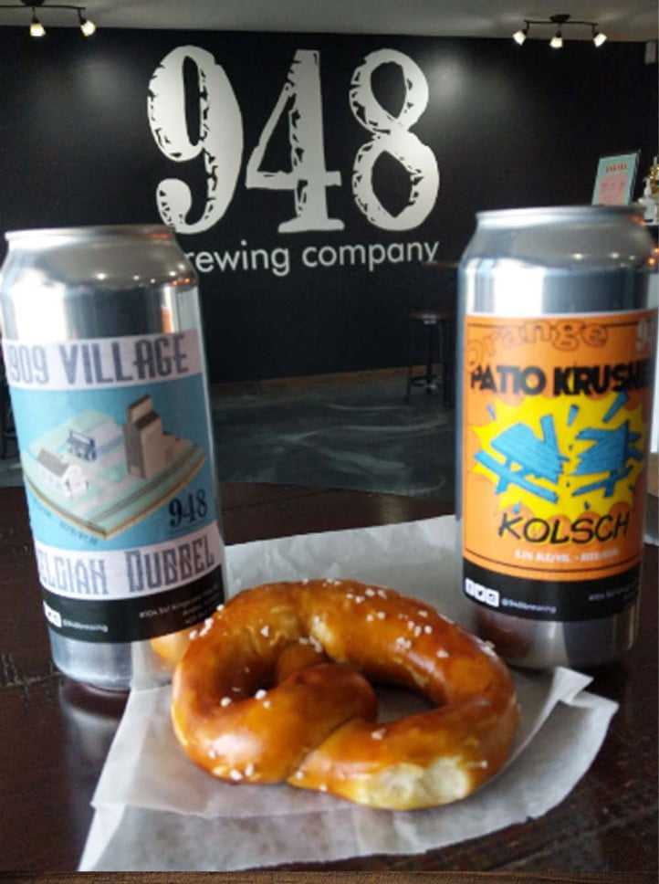Two 948 beer cans with a pretzel in the 948 taproom